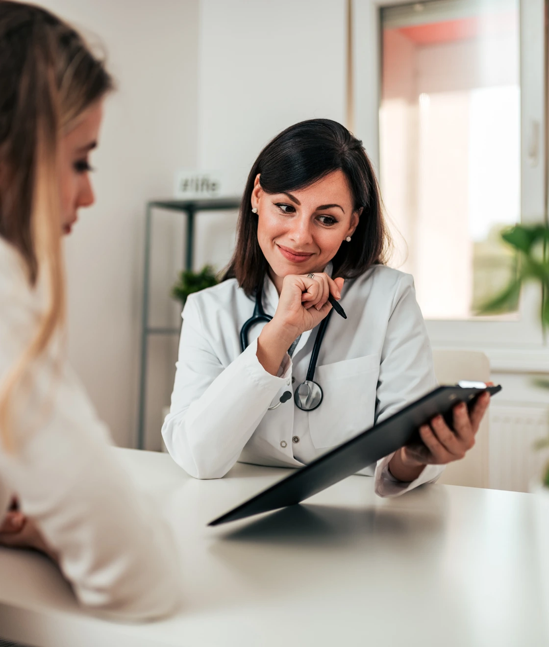 Female doctor smiling with stethoscope in clinic representing women’s health and gynecological care